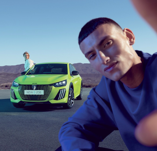 Joven hombre y mujer posando orgullosos frente a su nuevo Peugeot 208 en suscripción.